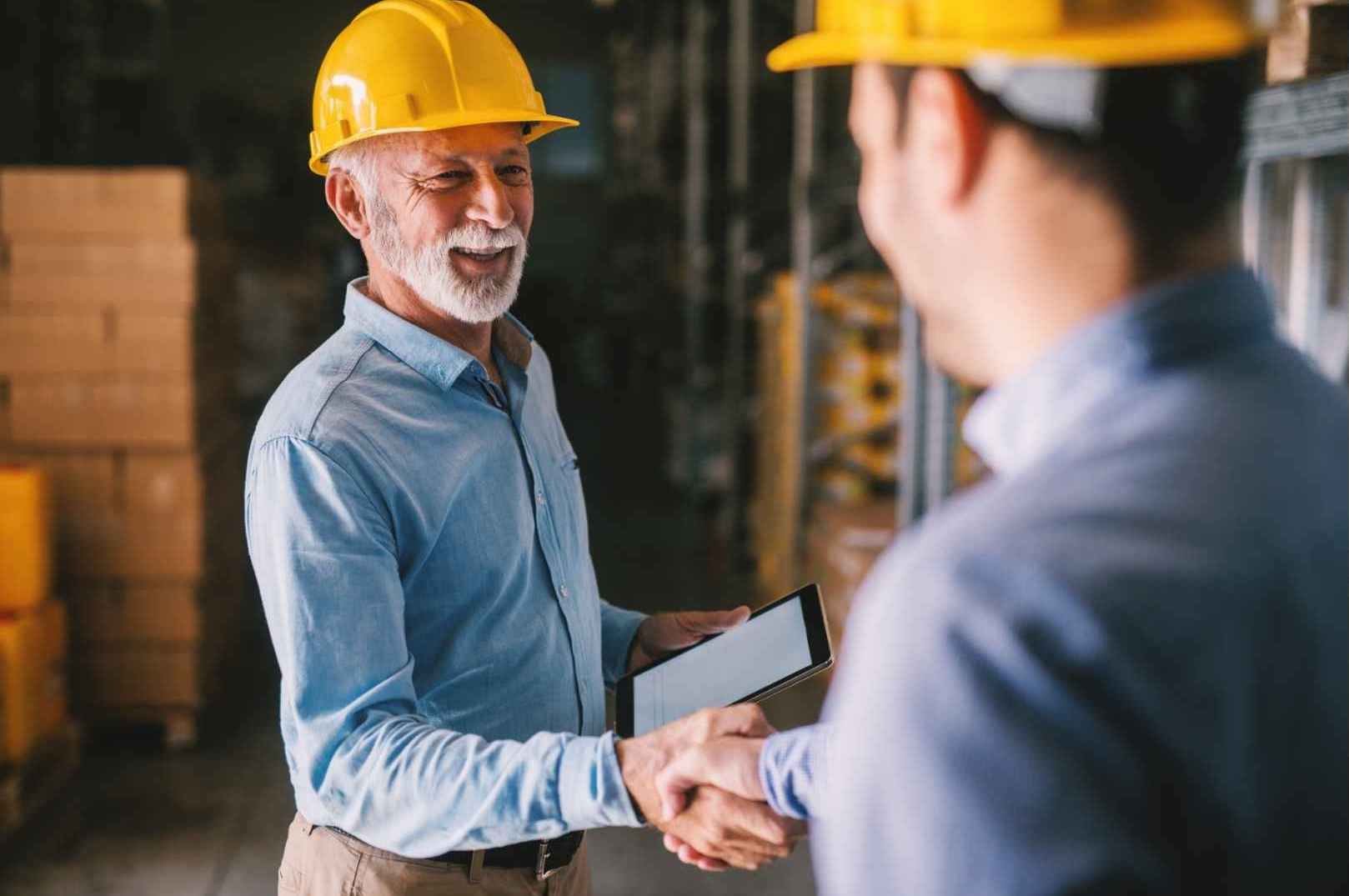 Two businessman shaking hands in warehouse